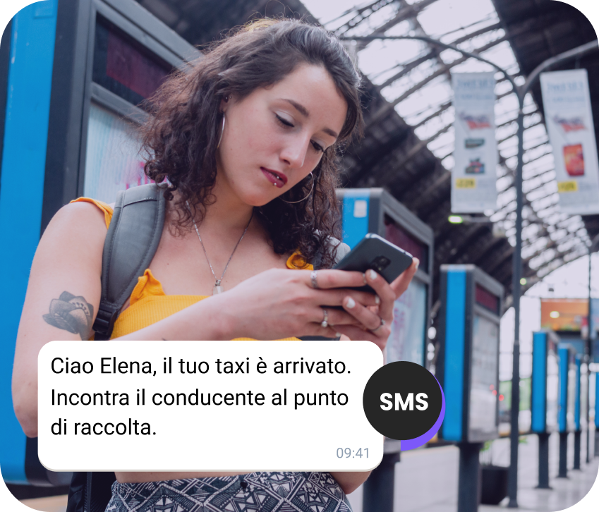 Ragazza con uno zaino alla stazione che controlla un SMS sul suo taxi in arrivo
