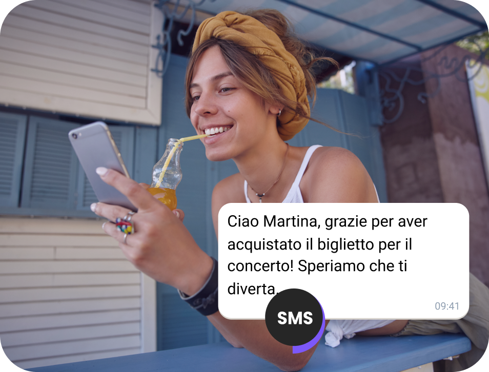 Ragazza che beve succo per strada controllando un SMS di conferma per un biglietto per un concerto